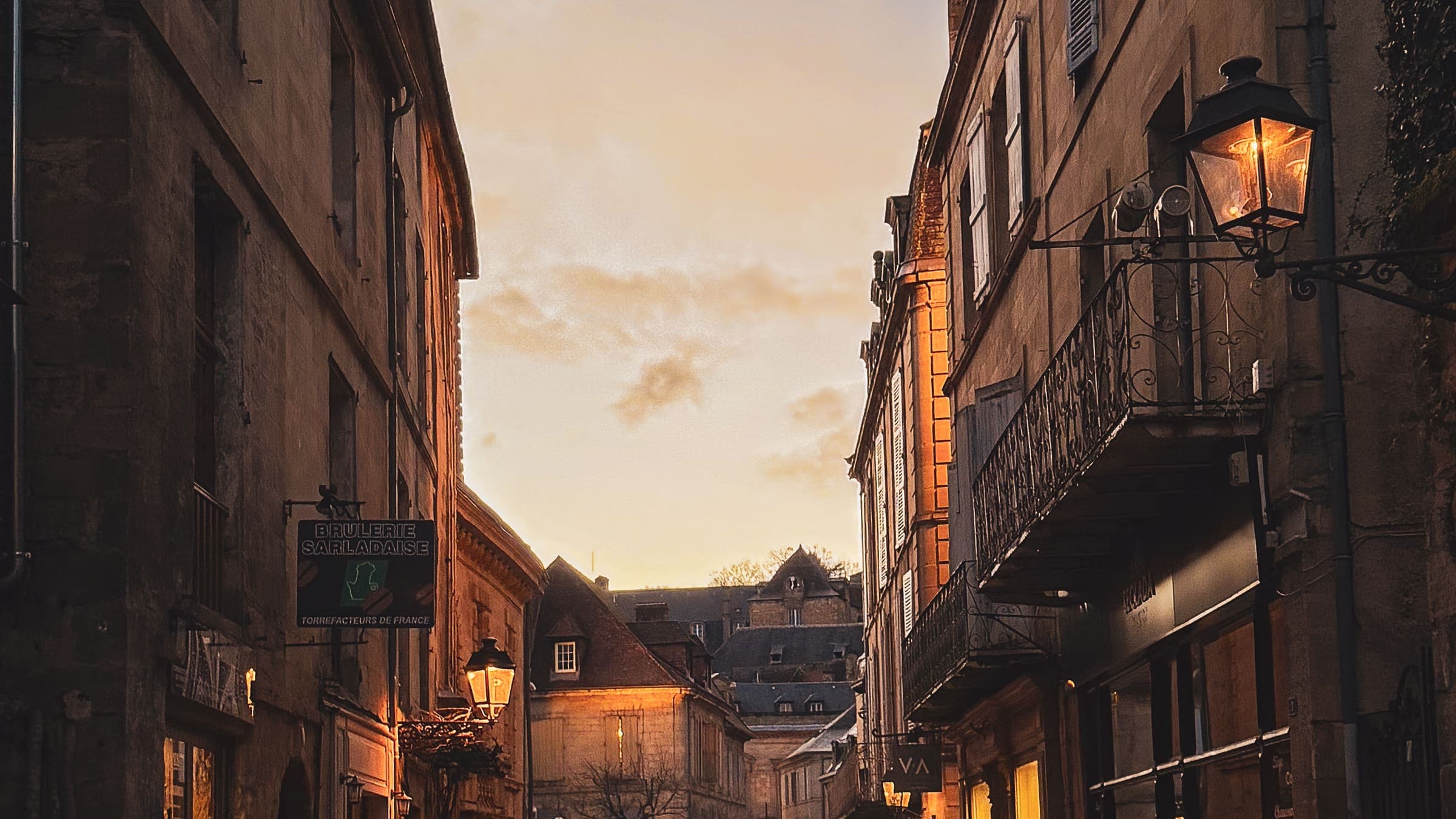 Ruelle pavée du centre historique de Sarlat, éclairée par les lampadaires au lever du jour